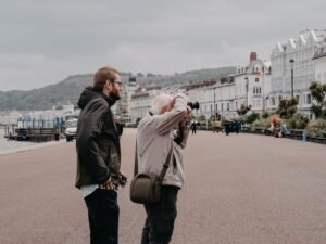 Senior traveler taking photos along a scenic seaside promenade while exploring one of the best travel destinations for seniors.