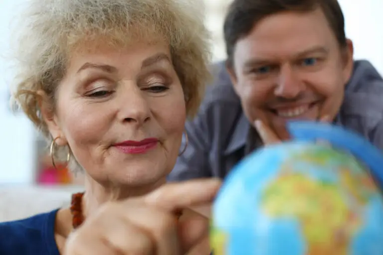 Close-up of senior woman and middle-aged man explore globe. Mother and son choose country for future travel. Modern technology and spare time together concept