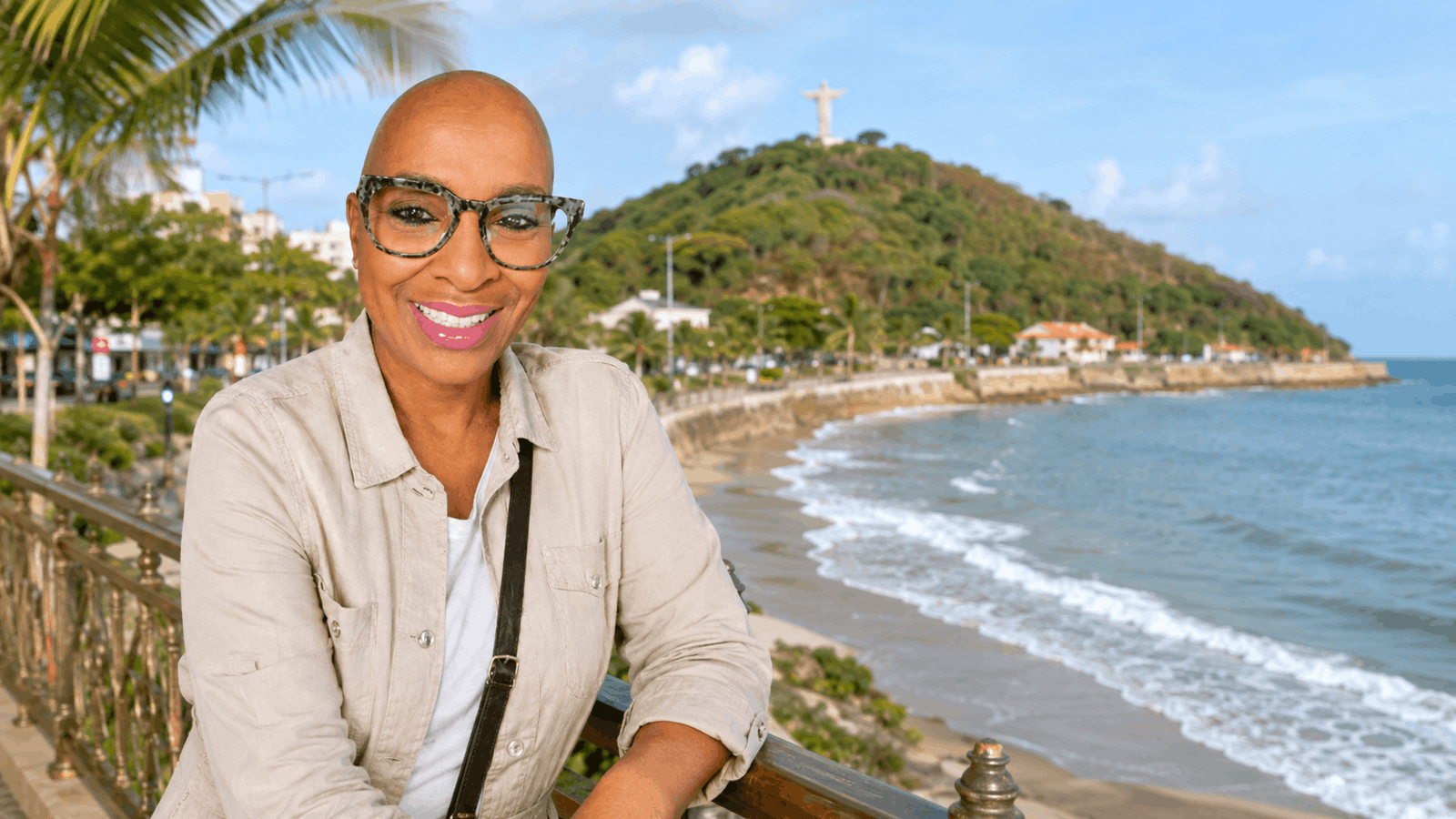 Smiling woman overlooking the Vung Tau coastline with beach and hillside statue in the background