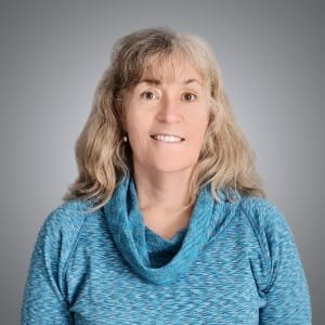 Melissa Jensen is smiling with a blue turtle neck top on.