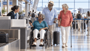Travel abroad with limited mobility: senior travelers using a wheelchair and cane check in at an airport with a companion.